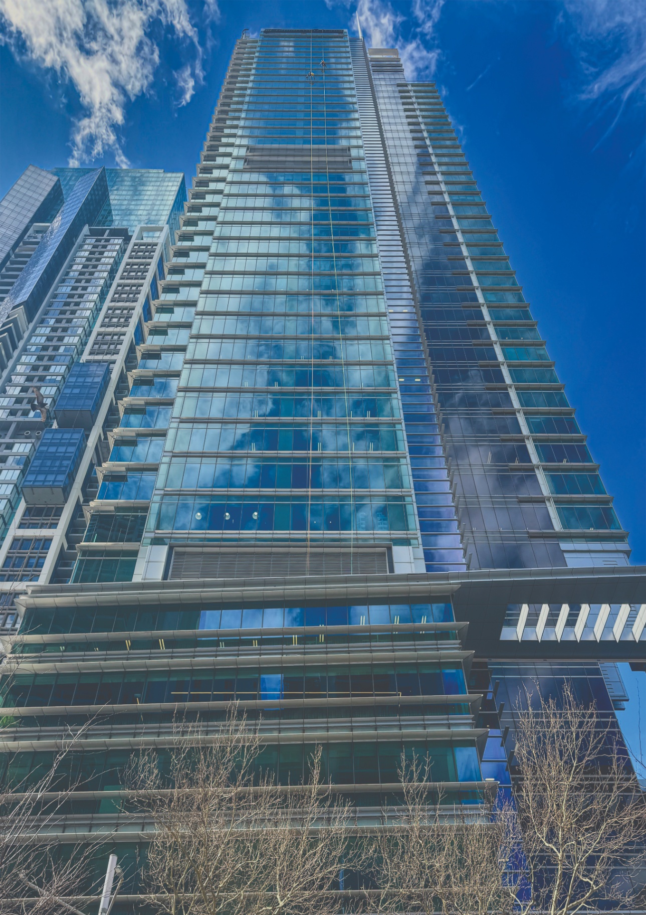 Modern glass high-rise tower reflecting clouds